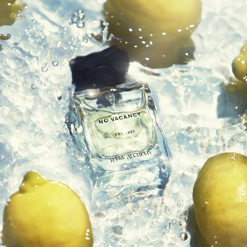 A bottle of perfume surrounded by water and lemons