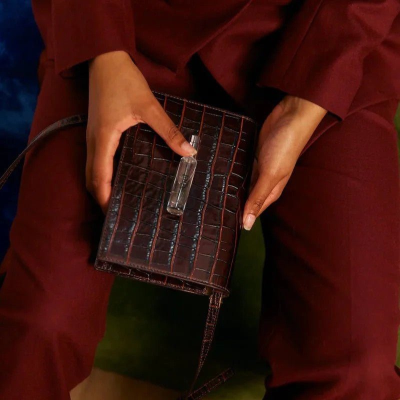 A woman holds a bottle of perfume on her lap