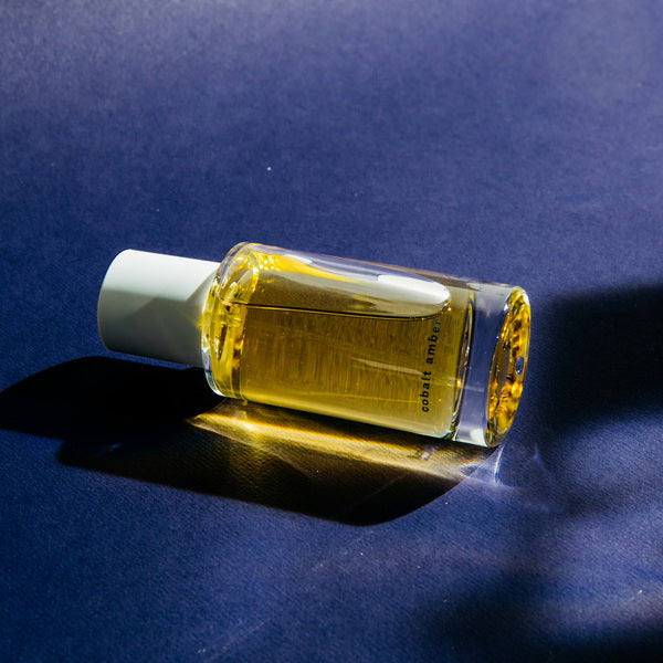 Abel Cobalt Amber Perfume lying flat on blue surface
