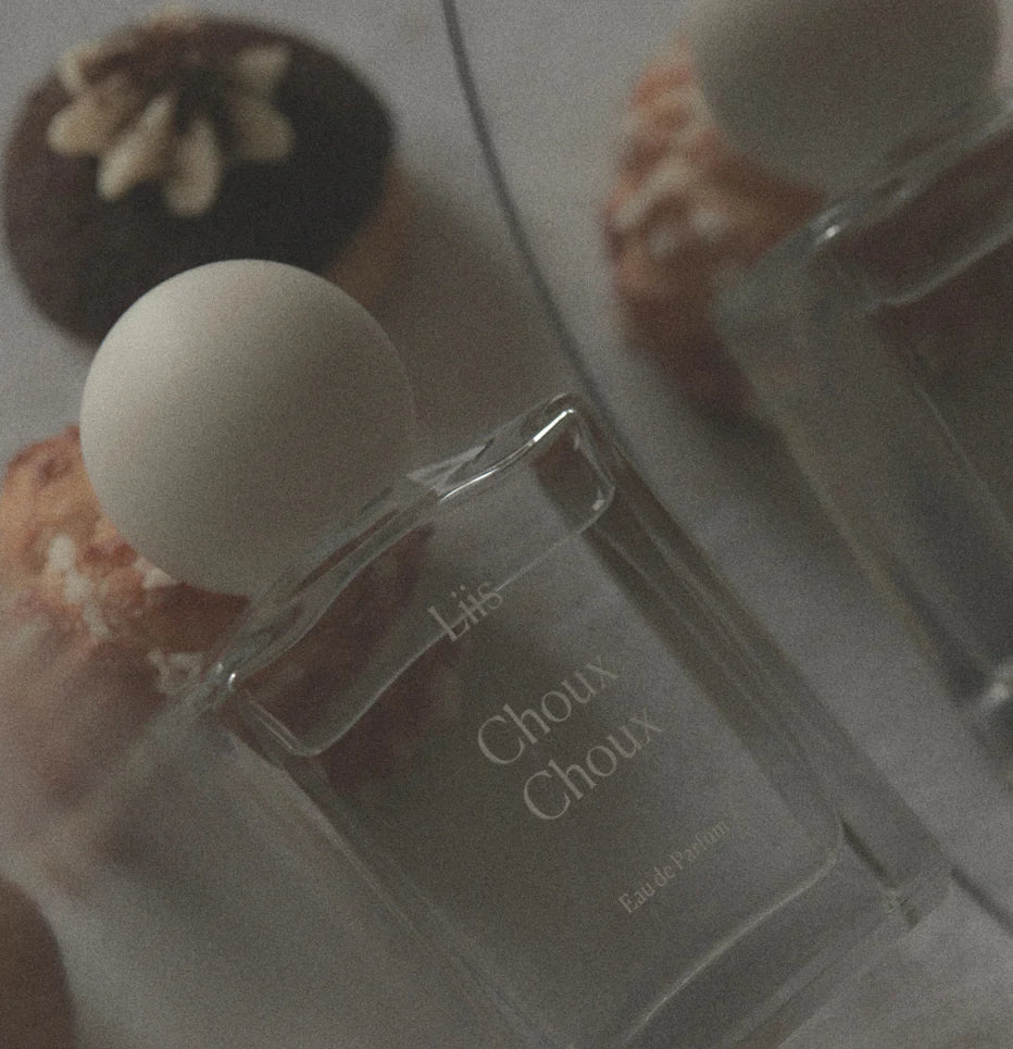 Liis Choux Choux Eau de Parfum Flakon in stimmungsvoller Nahaufnahme mit Gebäck im Hintergrund