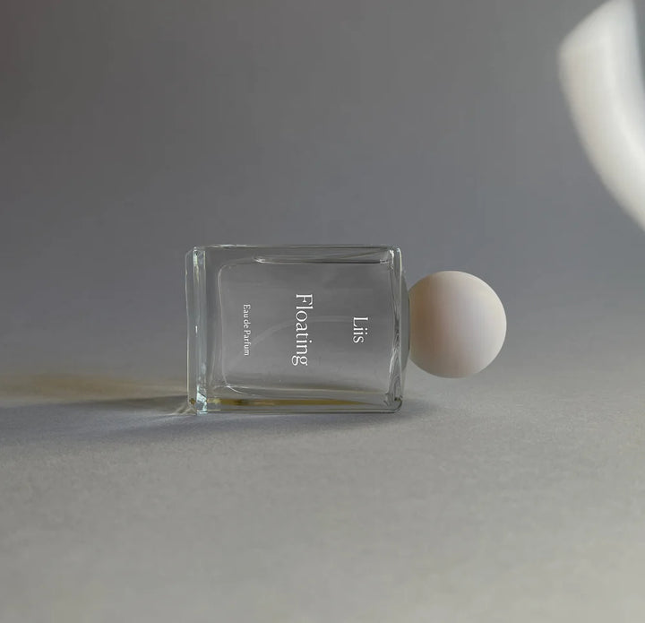 Liis Floating Eau de Parfum Flakon liegend auf dunklem Hintergrund