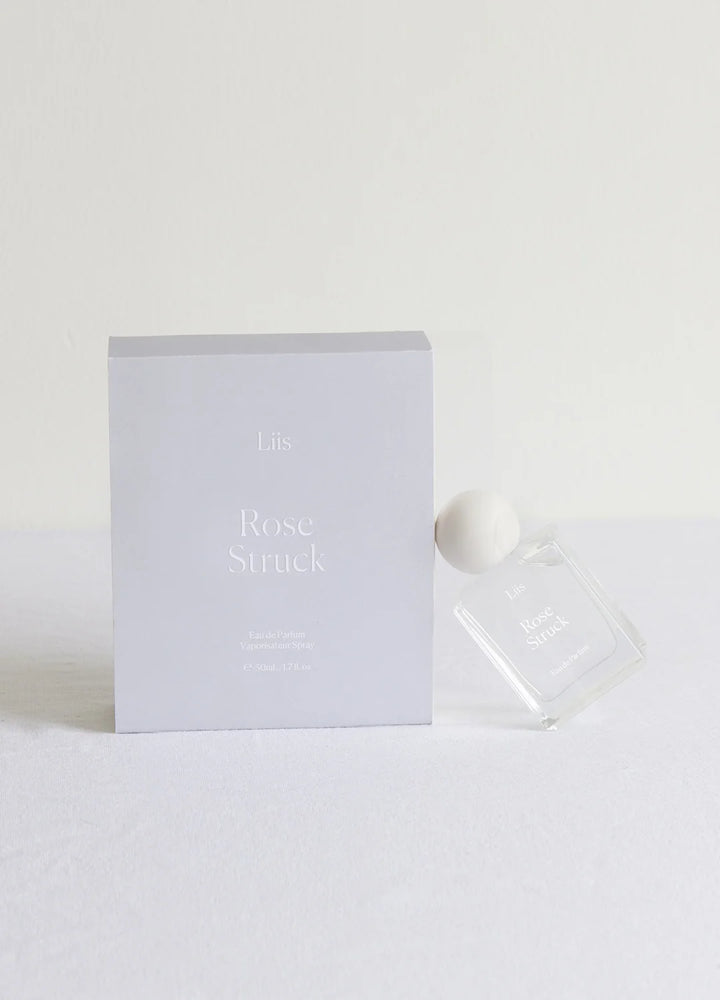 Liis Rose Struck Eau de Parfum Flakon minimalistisch vor hellem Flieder-Hintergrund