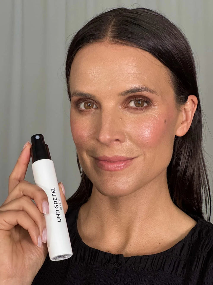 Hydrating & Setting Spray von Und Gretel - aufgetragen und von Model in Hand gehalten 