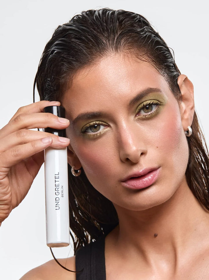 Hydrating & Setting Spray von Und Gretel - Model hält Produkt an Gesicht