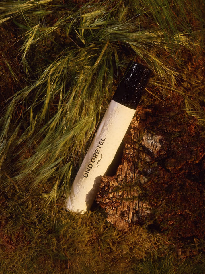 Hydrating & Setting Spray von Und Gretel - Produktfoto, auf Waldboden ähnlichem Hintergrund