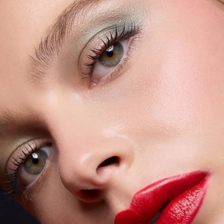 Nahaufnahme eines Models mit betonten Wimpern, schimmerndem Augen-Make-up und roten Lippen