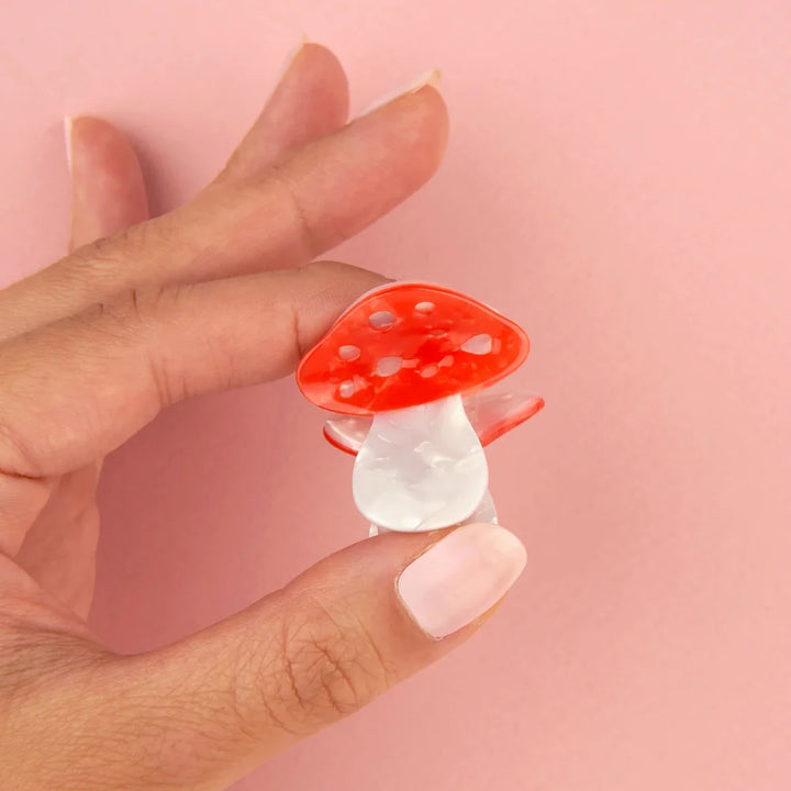 Coucou Suzette Mushroom Mini Hair Claw in Rot und Perlmutt auf einer Hand