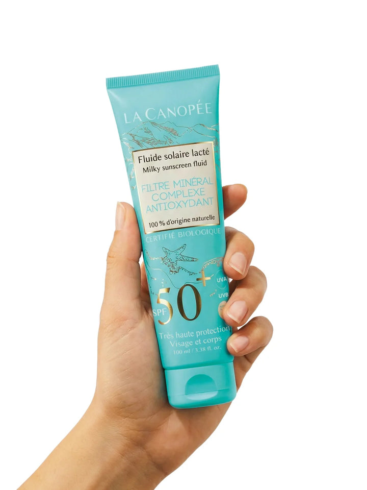 La Canopée Fluide Solaire Lacté SPF50+ in der Hand gehalten
