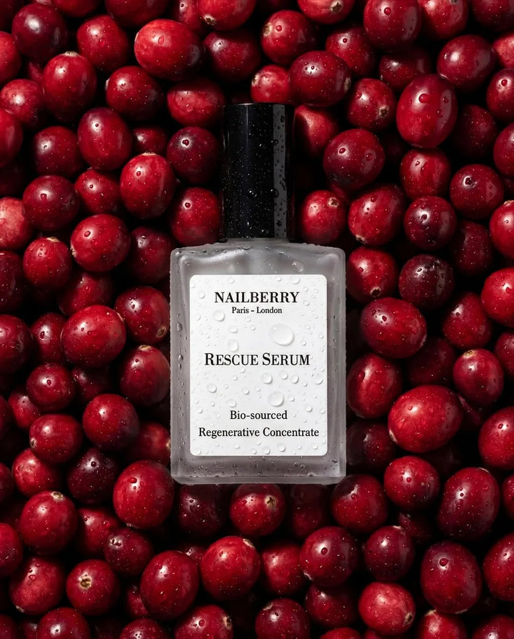 Rescue Serum von Nailberry - auf Untergrund mit Cranberries und mit Wassertropfen