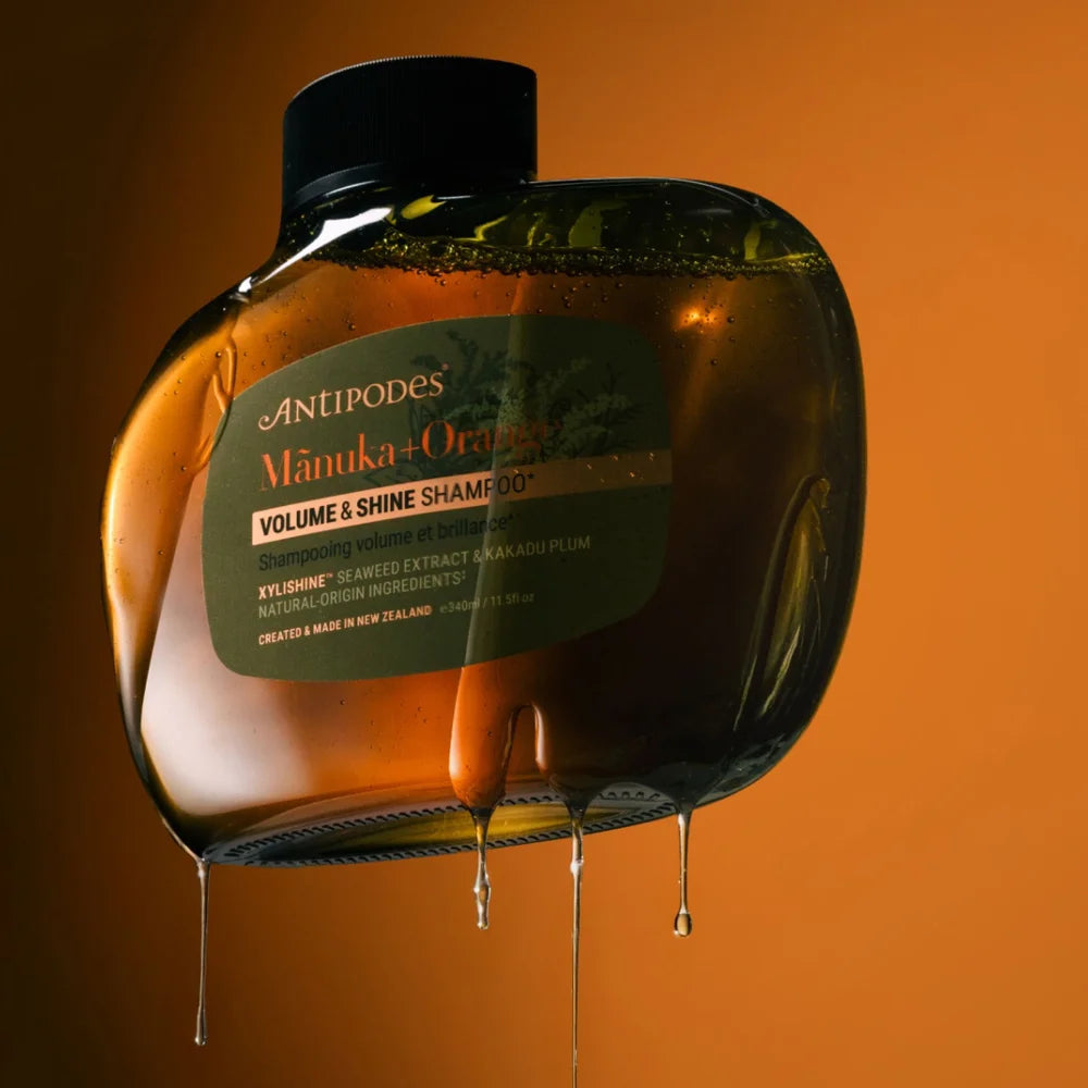 Antipodes Mānuka + Orange Volume & Shine Shampoo vor orangefarbenem Hintergrund