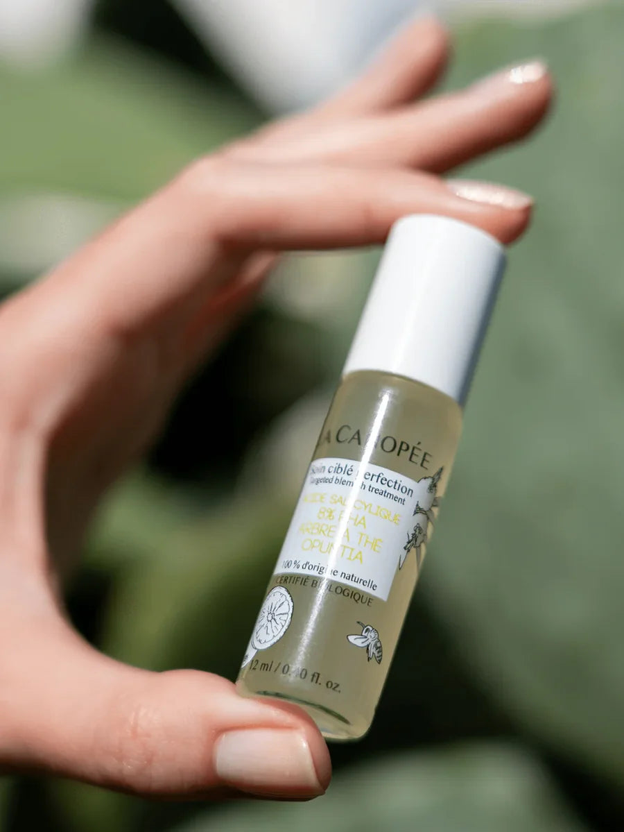 Hand hält den La Canopée Soin Ciblé Perfection Roll-on für punktuelle Pflege bei Unreinheiten