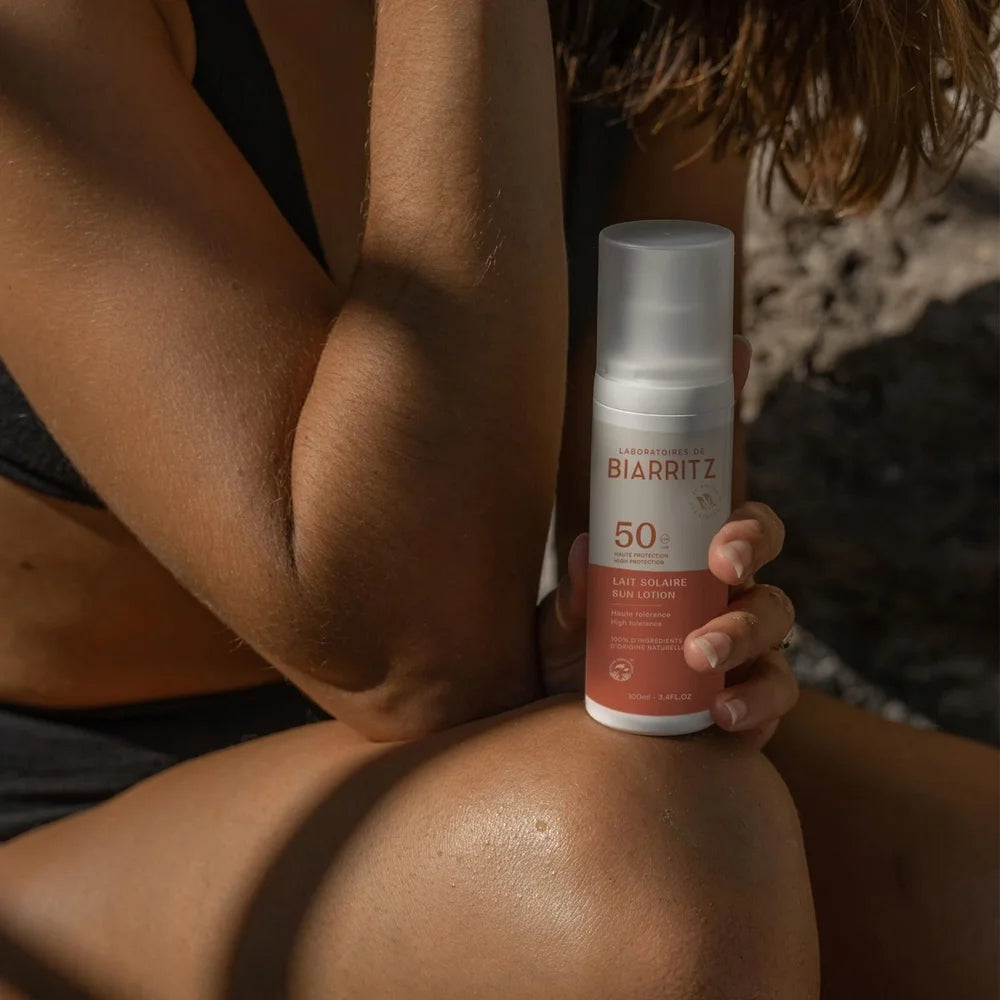 Sonnenmilch LSF 50 von Laboratoires de Biarriatz - in der Hand gehalten, auf Knie abgestellt