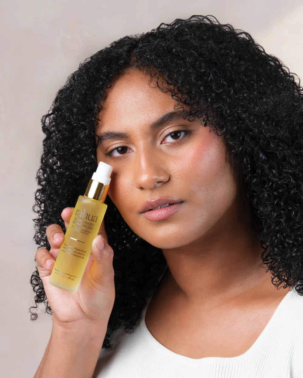 Frau mit lockigem Haar präsentiert Rahua Legendary Amazon Oil