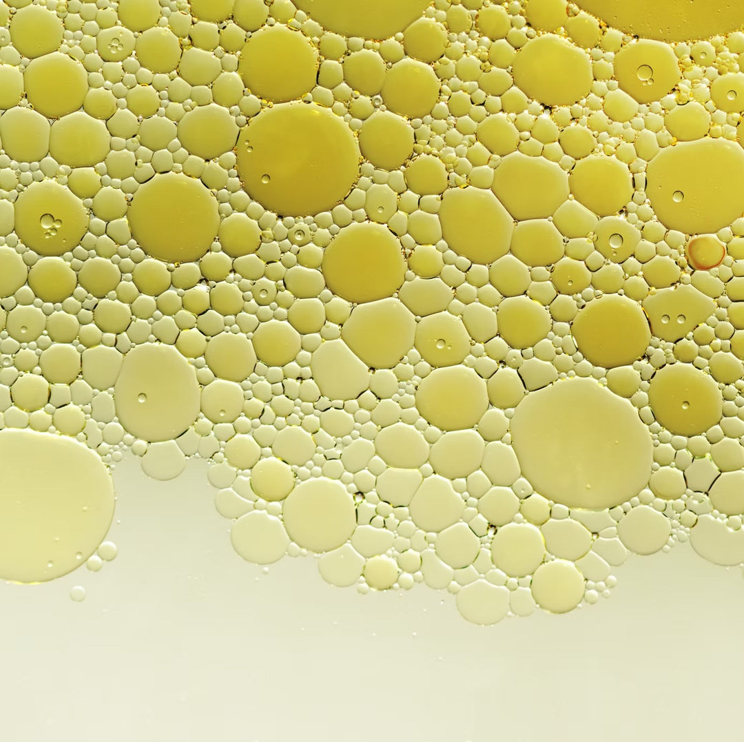 Texturaufnahme: goldgelbes Körperöl mit feinen Öltröpfchen (Makro)