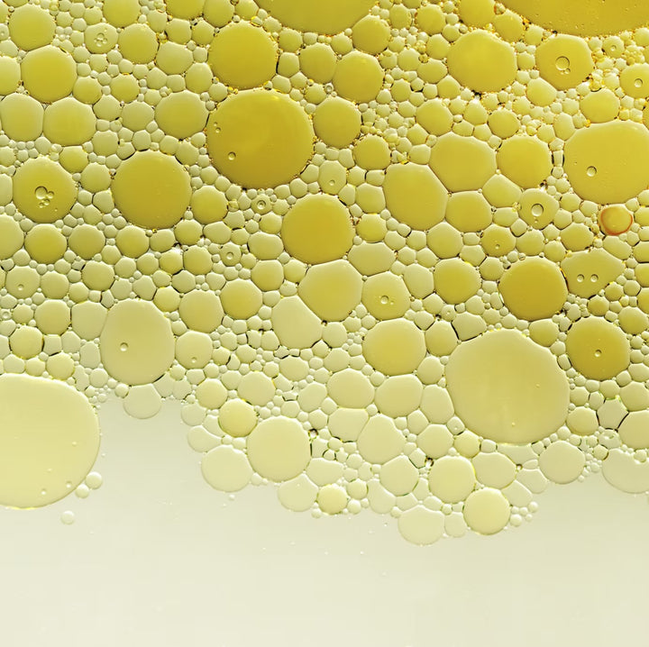 Texturaufnahme: goldgelbes Körperöl mit feinen Öltröpfchen (Makro)