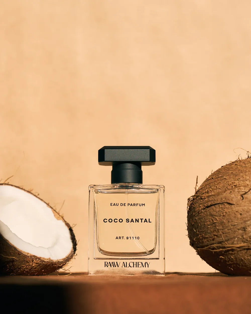 Coco Santal Eau de Parfum von RAAW Alchemy neben frischer Kokosnuss auf warmem Hintergrund