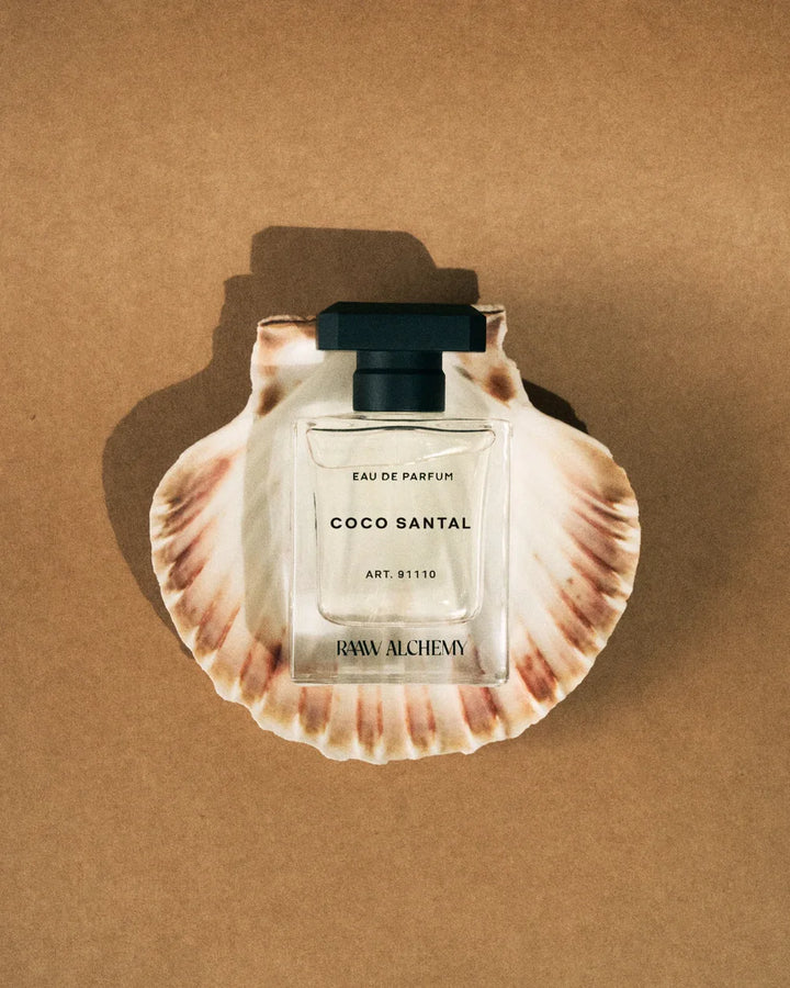 RAAW Alchemy Coco Santal Parfumflakon auf spiegelnder Muschel mit warmem Licht