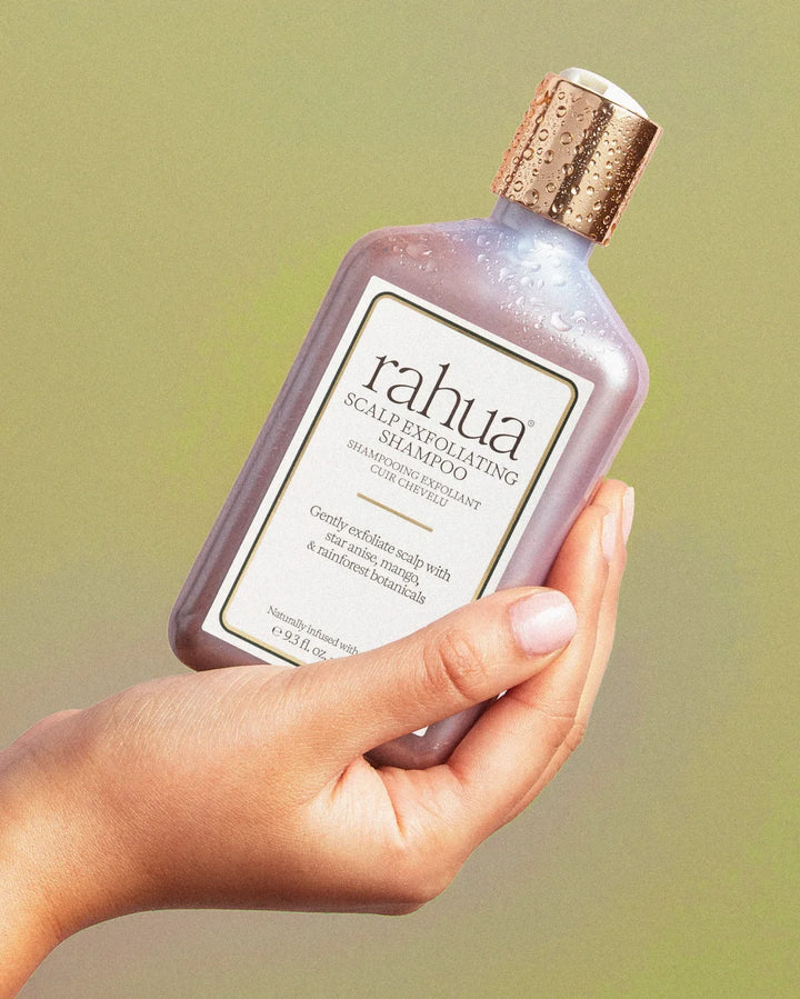 Hand hält Rahua Scalp Exfoliating Shampoo vor grünem Hintergrund