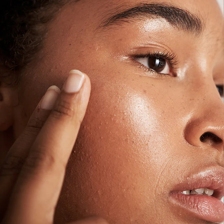 Frau trägt Champagne Dew Highlighter Balm auf Wangenknochen - natürlicher Glow-Effekt