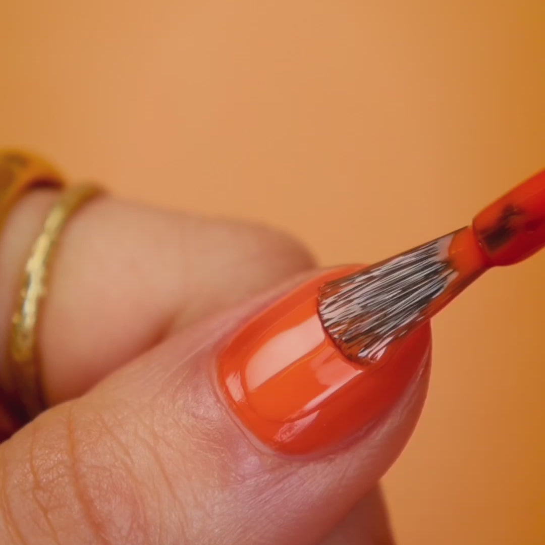 Maniküre mit dem Farbton Sunset: Der Nagellack in leuchtendem Korall-Orange wird gleichmäßig aufgetragen und hinterlässt ein glänzendes, lebendiges Finish, das sommerlich und ausdrucksstark wirkt - Video