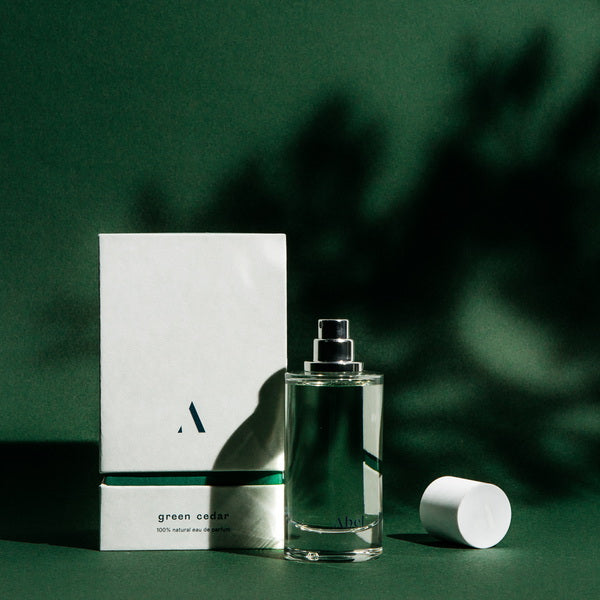 Abel Perfume Green Cedar lifestyle image in front of green background with shadows