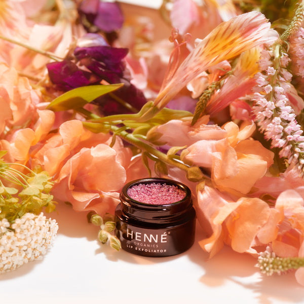 Henné Organics Exfoliant pour les lèvres Rose Diamonds devant un bouquet de fleurs