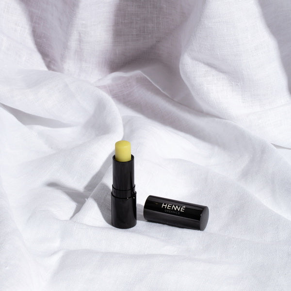 Henné Organics Luxury Lip Balm V2 - stick aperto davanti al lino