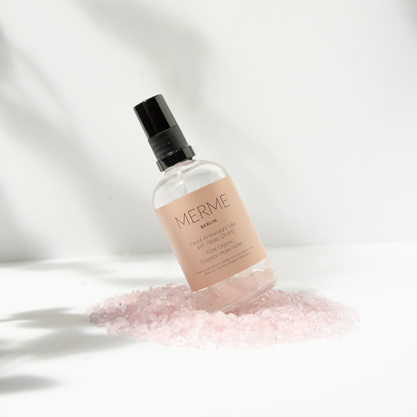 Merme Berlin Facial Antioxidant Mist With Rose Quartz 100% Organic Rosewater standing on rose quartz pepples