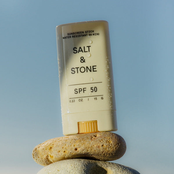 Salt & Stone Barra facial de protección solar con color SPF 50 15 g - primer plano con gotas de agua